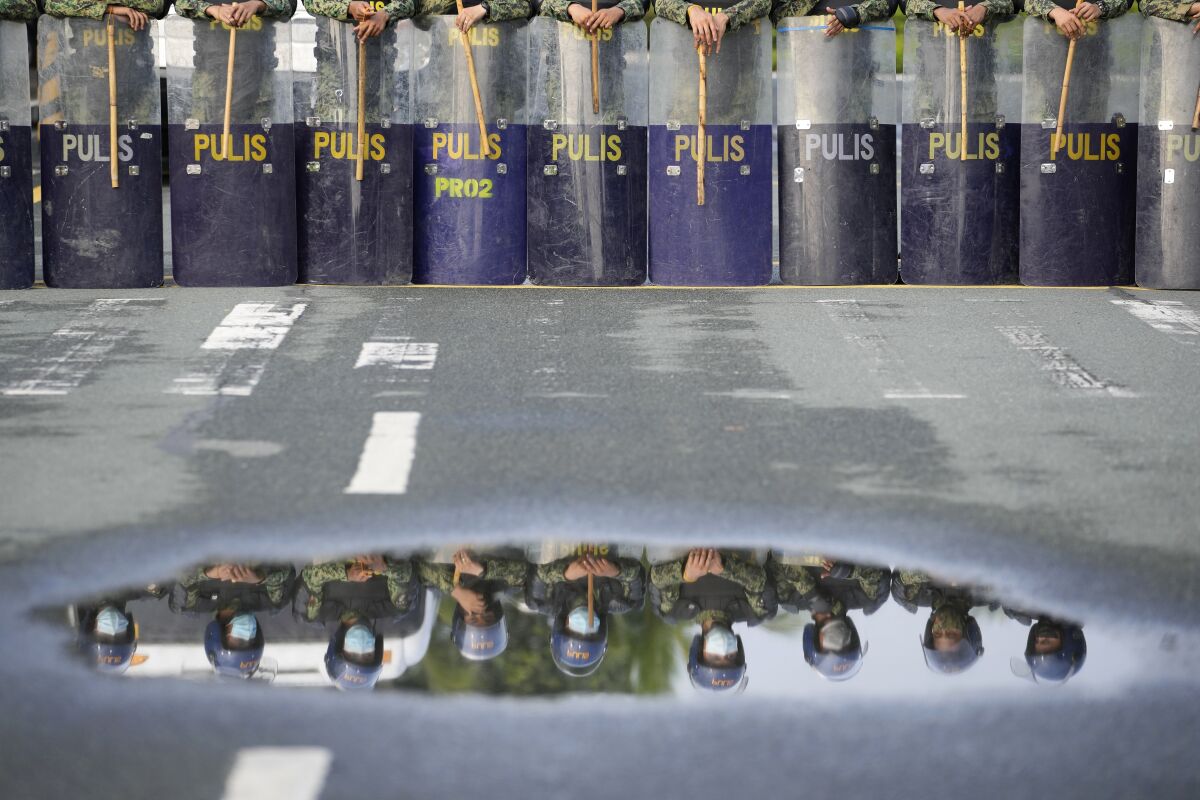 Police are reflected on water as they secure the area where politicians will file their certificate of candidacy before the Commission on Elections on Friday, Oct. 1, 2021 in Manila, Philippines. Friday marks the start of a weeklong registration period for candidates seeking to lead a Southeast Asian nation that has been hit hard by the pandemic and deep political conflicts.(AP Photo/Aaron Favila)
