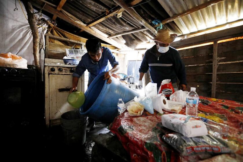 Francisco Ocadiz, 16, left, along with his father, Sergio Ocadiz, empties a 50-gallon drum into buckets so he can go retrieve more water for the family's home in the La Conchita neighborhood of Xochimilco.