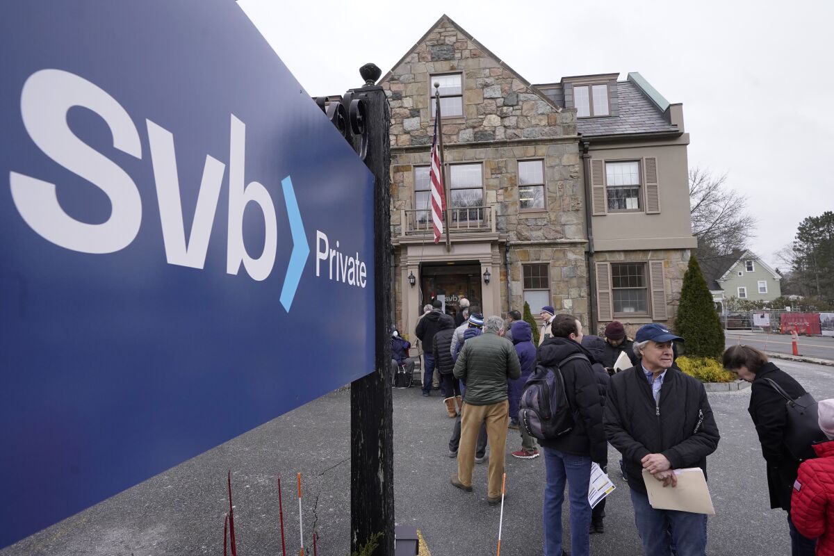 Customers line up outside a Silicon Valley Bank branch in Wellesley, Mass., on Monday