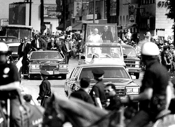 Police on horseback and Secret Service agents surround Pope John Paul II as he rides in the popemobile on Spring Street in Chinatown during his visit to Los Angeles in September 1987.