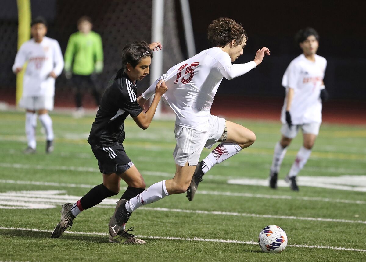 Costa Mesa defender Carlos Alcala gets a hand full of Estancia defender Gabe Johner's jersey as he makes a run on Friday.