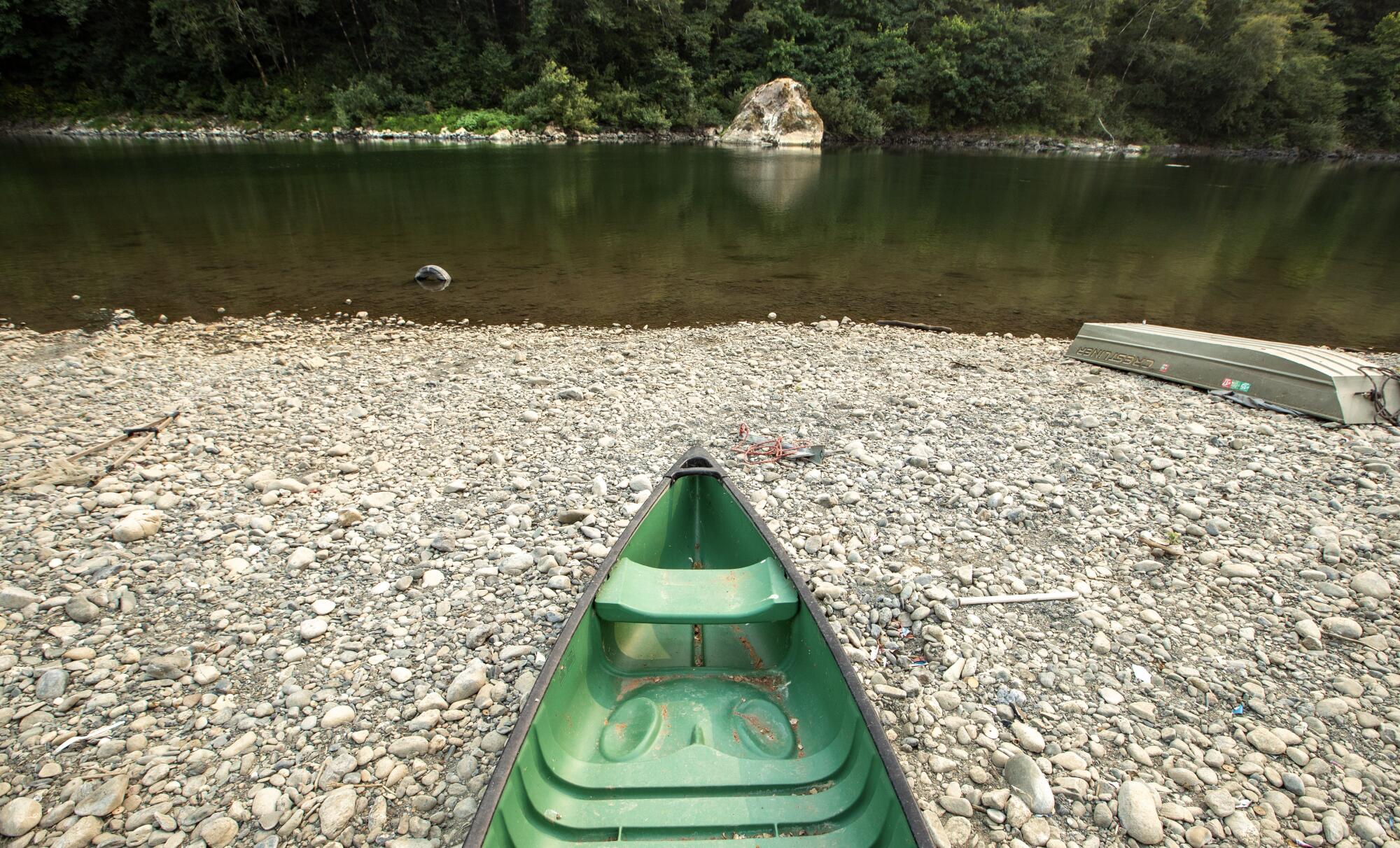 A canoe rests on on a river bank.