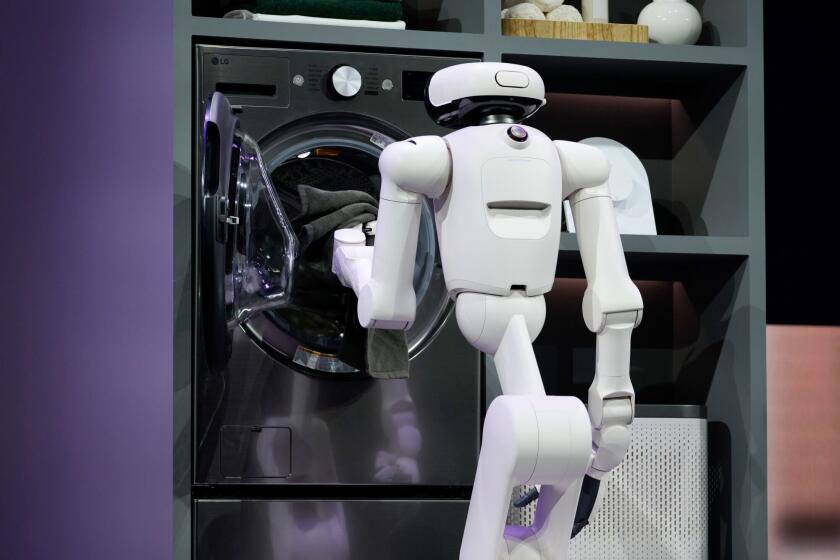 An LG Electronics CLOiD home robot puts a towel in a washing machine during the 2026 CES event in Las Vegas. Photographer: Bridget Bennett/Bloomberg