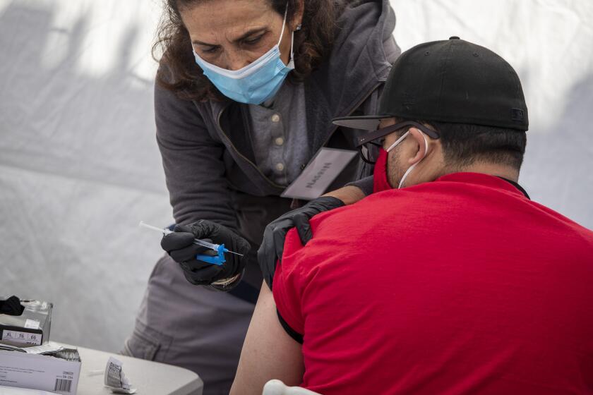 LOS ANGELES, CA - MARCH 18: Pharmacist Nasrin Assil, left, administers a Johnson & Johnson COVID-19 vaccine at Karsh Family Social Service Center's pop-up clinic for older adults in the neighborhood on Thursday, March 18, 2021 in Los Angeles, CA., left. (Brian van der Brug / Los Angeles Times)