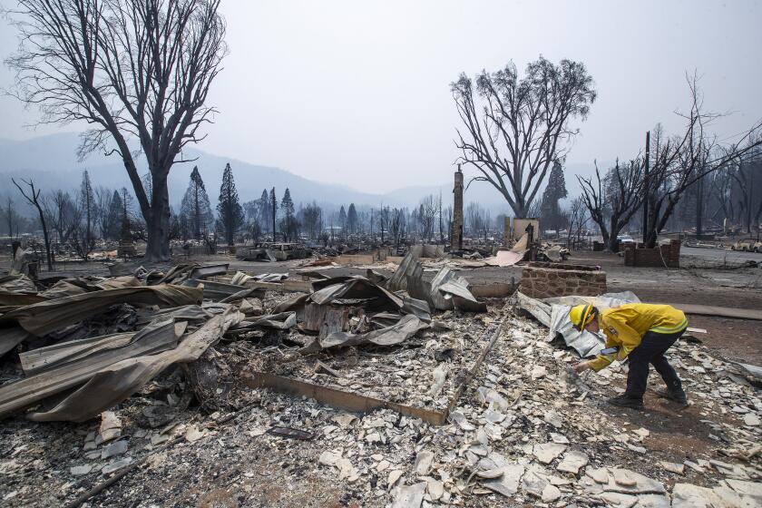 GREENVILLE, CA - AUGUST 08, 2021: Amanda Peri, an inspector with Cal Fire Shasta Trinity Unit, searches thru the debris to determine what material the roofs of homes were made out of that burnt down in the town of Greenville as a result of the Dixie Fire. (Mel Melcon / Los Angeles Times)
