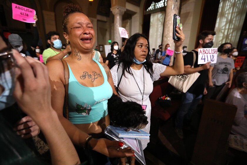 A woman cries amid a crowd of protesters holding signs inside a building.