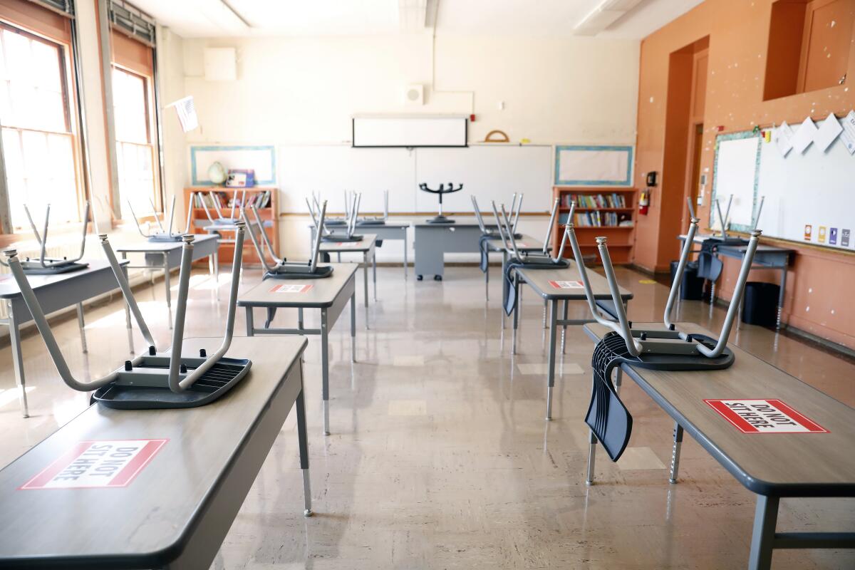 An empty classroom with seats on top of desks.