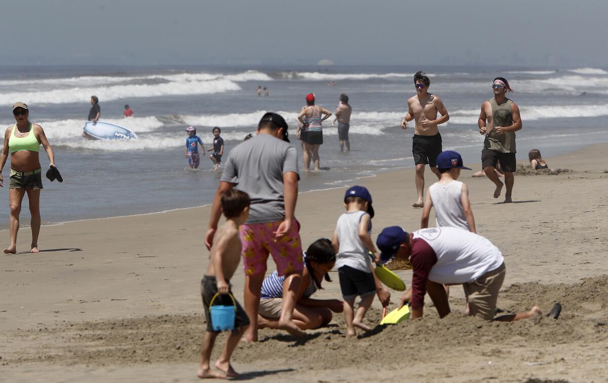 Beach goers play along the coast on the north side of Huntington Beach Pier on Friday.