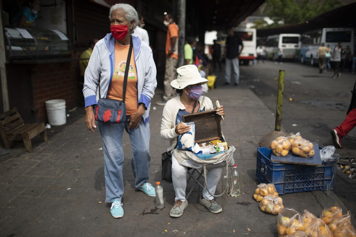 Vendedores callejeros usan mascarillas para protegerse del nuevo coronavirus mientras esperan clientes 