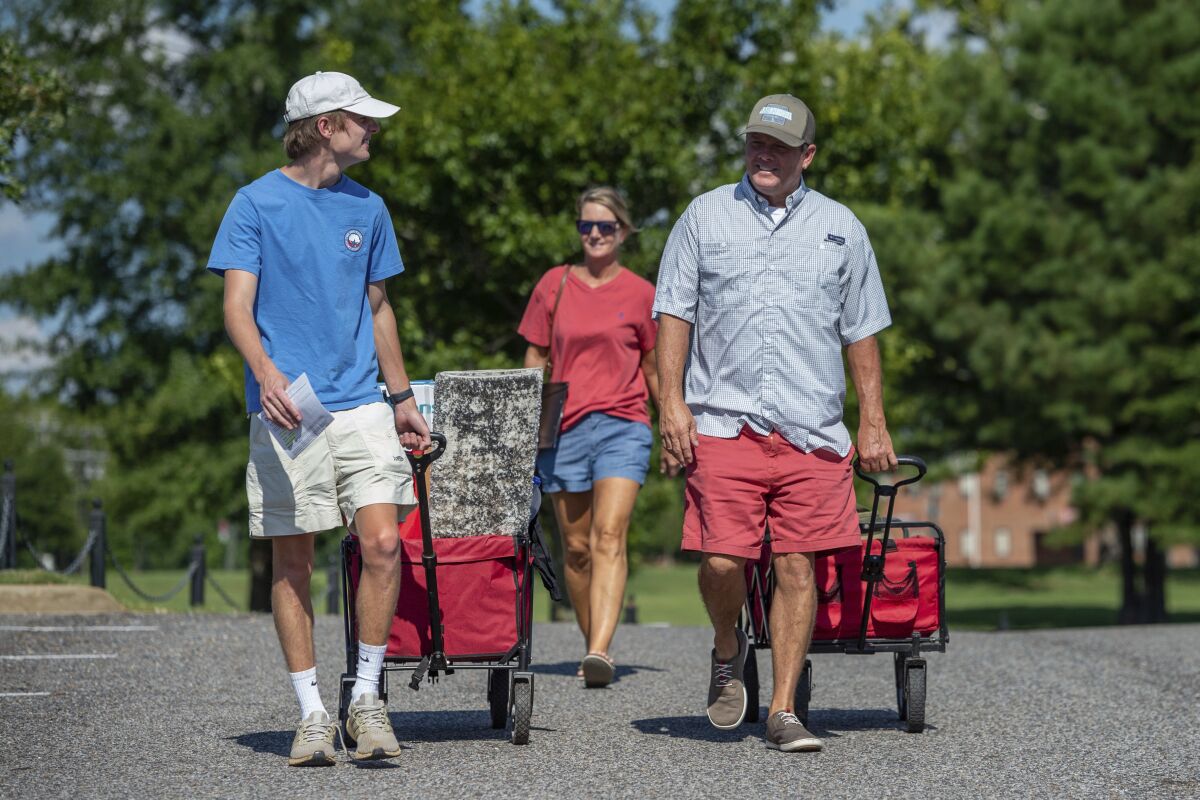 Baylor Garland, left, arrives to move in for his freshman year, assisted by his father Alan, right and mother, Teena, after they arrived from Eaton, Ga., at the University of Alabama on Saturday, Aug. 15, 2020, in Tuscaloosa, Ala. More than 20,000 students returned to campus for the first time since spring break with numerous school and city codes in effect to limit the spread of COVID-19. (AP Photo/Vasha Hunt)