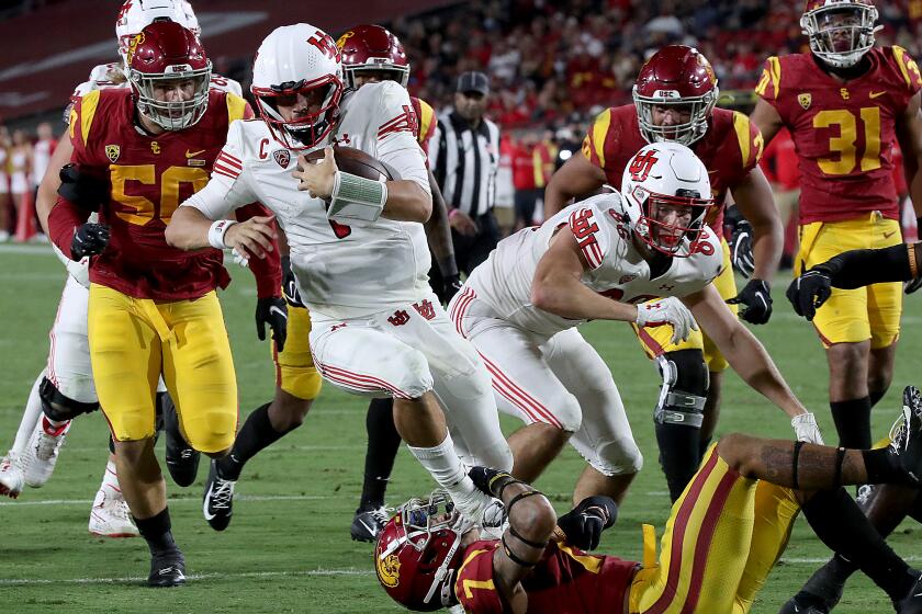 LOS ANGELES, CALIF. - OCT. 9, 2021. Utah quarterback Cameron Rising runs over USC strong safety Chase Williams en route to a touchdown in the second half at the Los Angeles Memorial Coliseum on Saturday, Oct. 9, 2021. (Luis Sinco / Los Angeles Times)