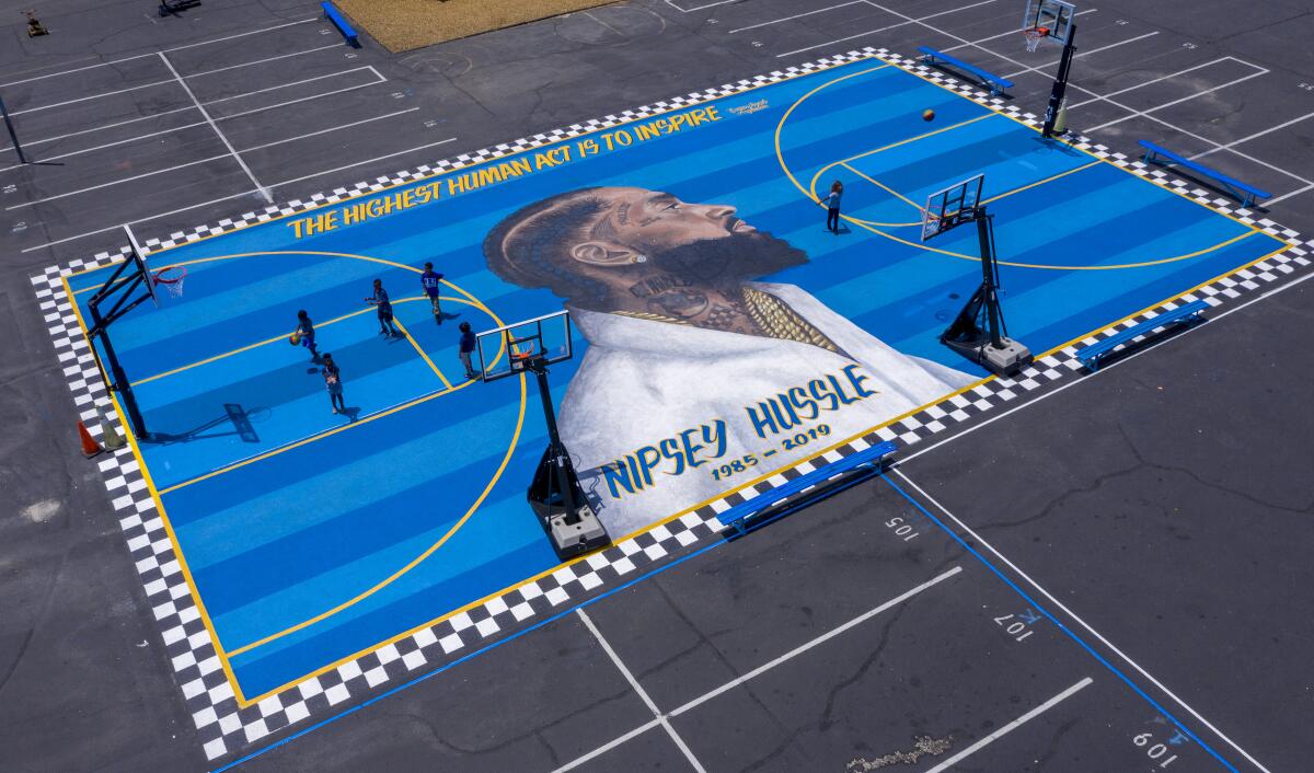 Children at the Crete Academy play basketball on a court painted with a mural honoring slain rapper Nipsey Hussle