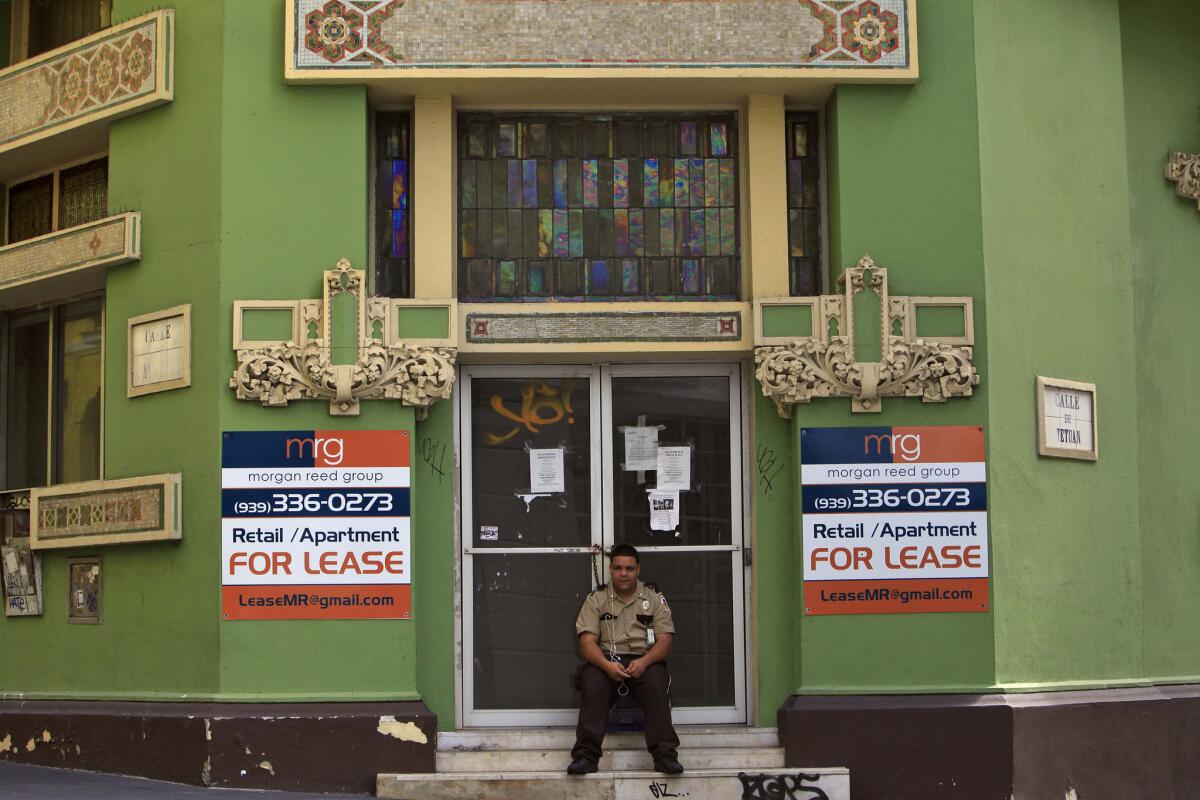 Un guarda de seguridad privada se sienta ante un negocio cerrado en el distrito colonial de Viejo San Juan, Puerto Rico, el domingo 2 de agosto de 2015. Durante la actual crisis económica, la adeudada firma puertorriqueña de electricidad ya cobra tarifas que suponen el doble de la media en el continente, y está bajo presión de sus tenedores de bonos de que suba más los precios.