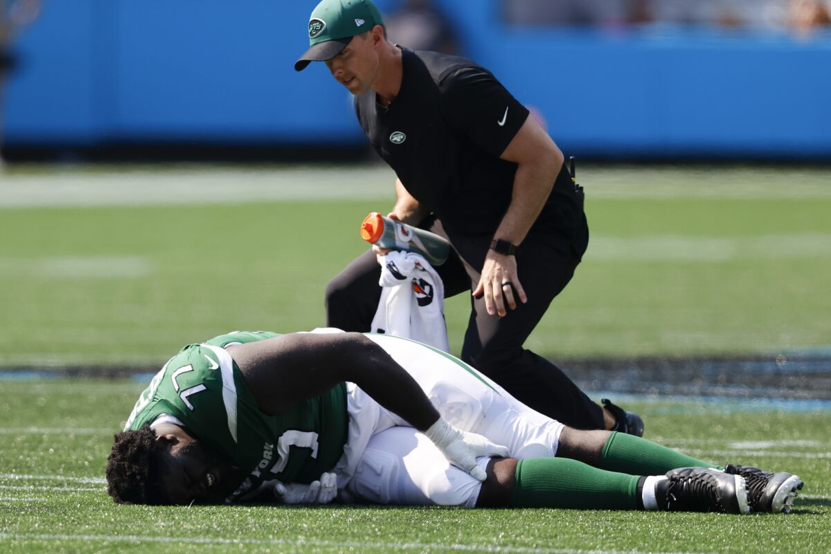 New York Jets offensive tackle Mekhi Becton is helped on the field during the second half of an NFL football game against the Carolina Panthers Sunday, Sept. 12, 2021, in Charlotte, N.C. (AP Photo/Nell Redmond)