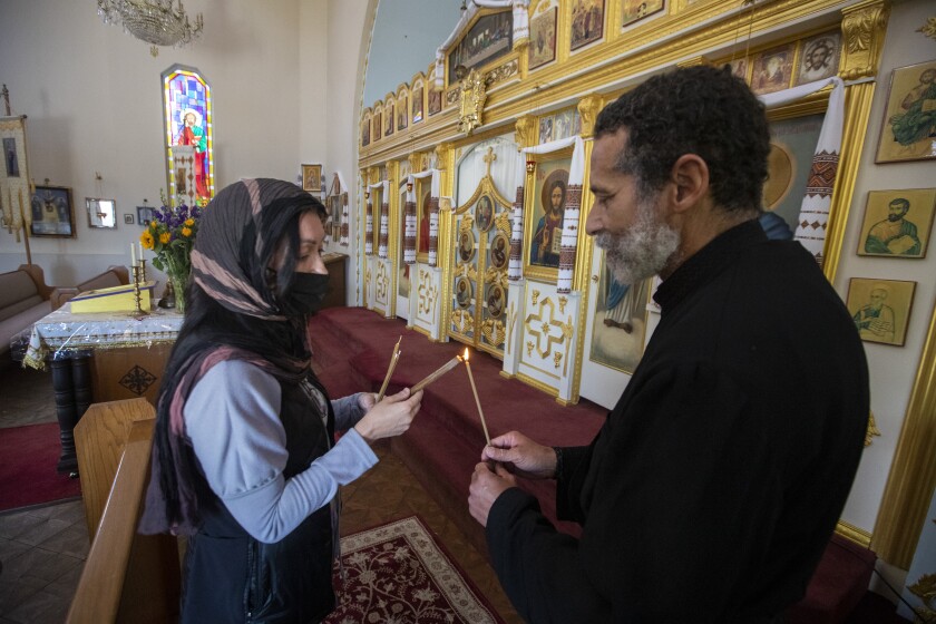 Subdeacon David De Jesus, right, lights a candle for a visitor before Mass