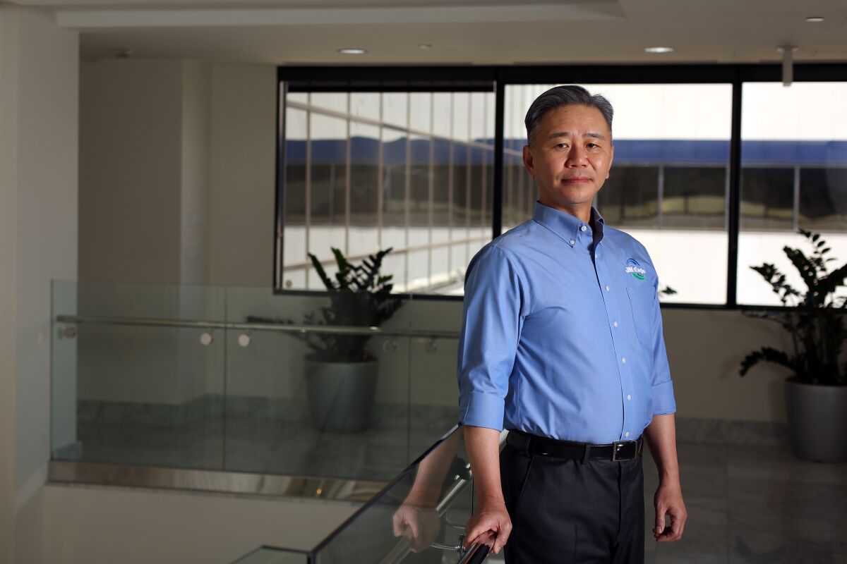 Walter Wang stands in a blue shirt next to a glass top table.