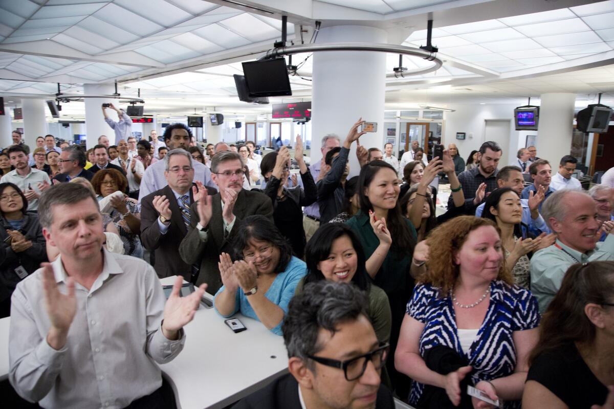 Associated Press employees applaud as the AP wins the Pulitzer Prize for public service Monday in New York.