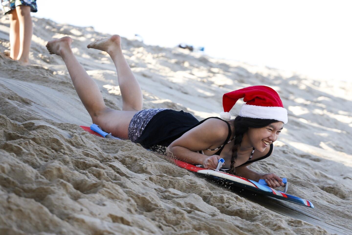 Kiana Kim, 14, of Redondo Beach sleds down a sand dune at the Hermosa Beach pier in the afternoon of Christmas Day.