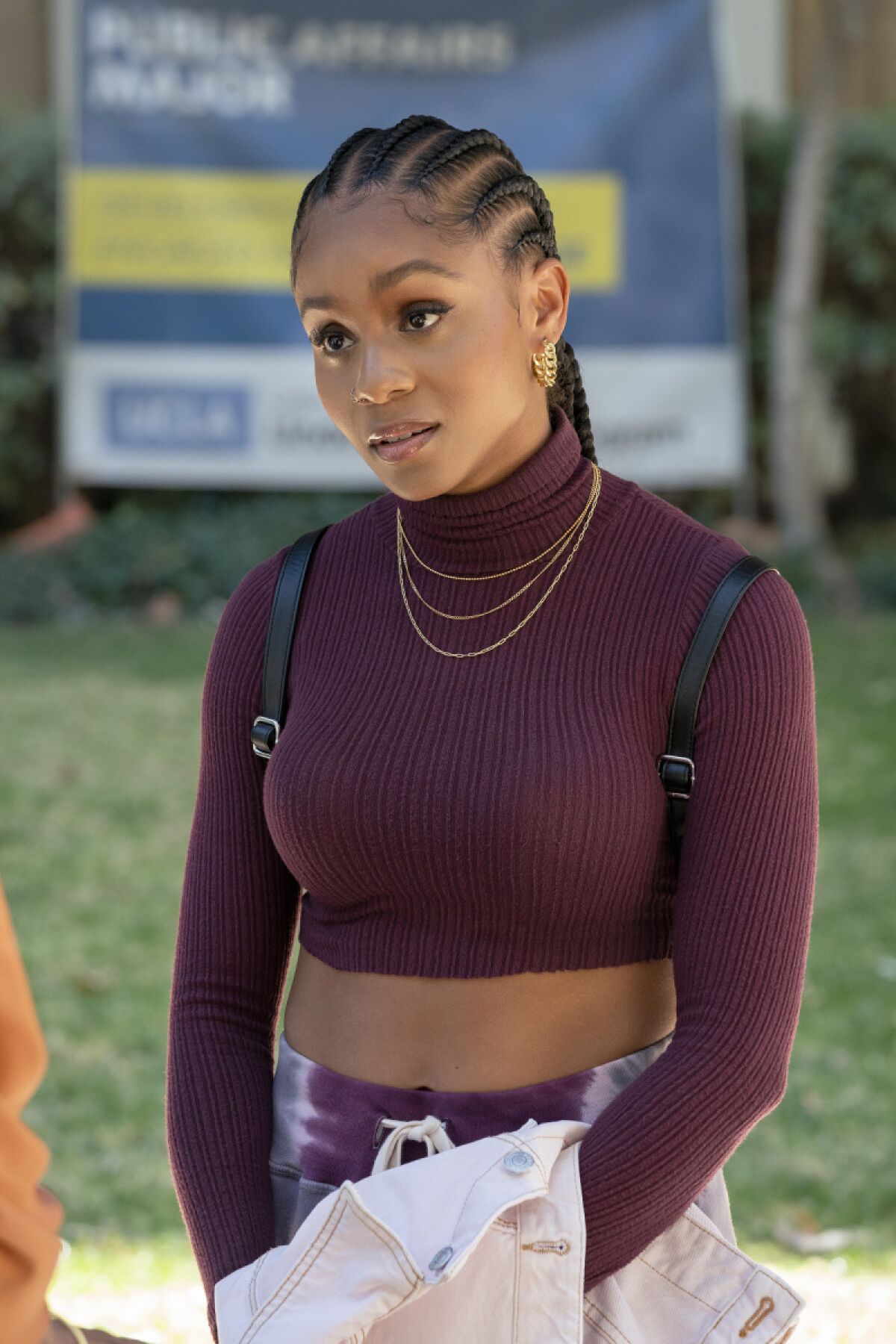 A young woman in a purple crop top turtleneck sweater with gold necklaces