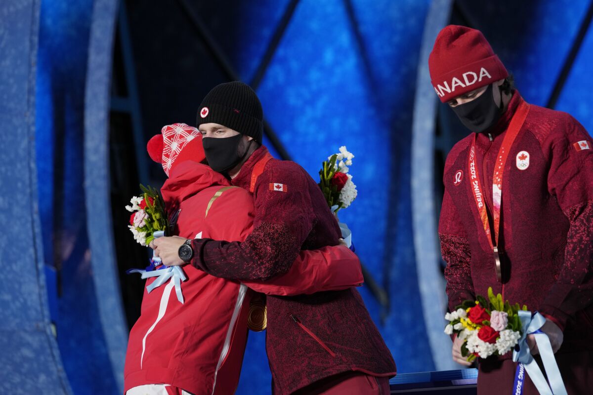 Silver medalist China's Su Yiming, left, embraces gold medalist Canada's Max Parrot during a medals ceremony for the men's snowboard slopestyle event at the 2022 Winter Olympics, Monday, Feb. 7, 2022, in Zhangjiakou, China. (AP Photo/Aaron Favila)