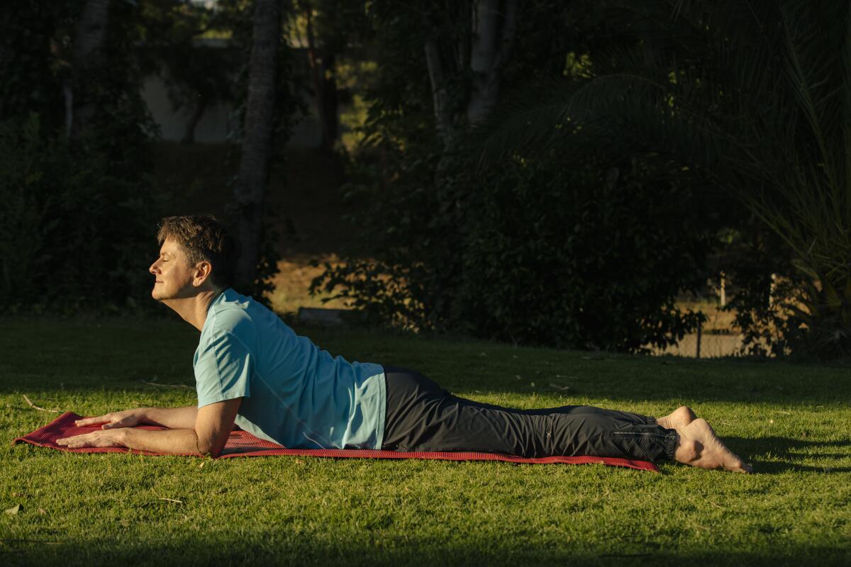 A man lies on his stomach, propping his upper body up on his arms, in a park.