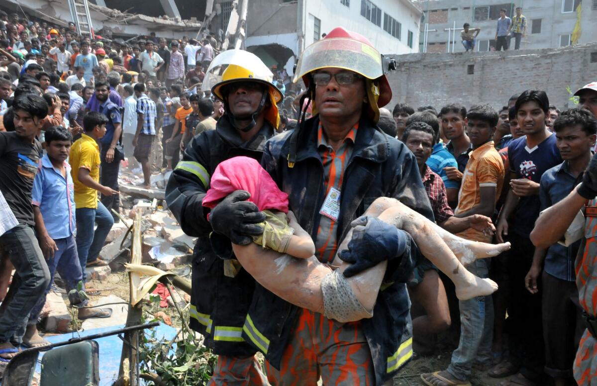 A rescuer carries an injured boy from the rubble of Rana Plaza on April 24, 2015 in Dhaka, Bangladesh. The eight-story commercial building collapsed, killing over a thousand people and thousands more injured. Authorities in Balgladesh charged 42 people with murder on Monday in the collapse, including the building's owner. (Shariful Islam/Xinhua/Zuma Press/TNS)