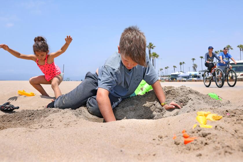 PLAYA DEL REY-CA-MAY 24, 2024: MacKenzie Bergman, 4, of Hesperia, left, and Charlie Young, 12, of Eastvale, center, kick off Memorial Day weekend playing in the sand while camping with their families at Dockweiler State Beach in Play del Rey on May 24, 2024. (Christina House / Los Angeles Times)
