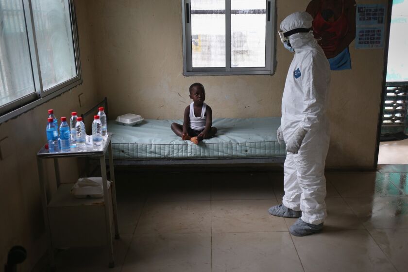 A health worker speaks with a boy at a center for suspected Ebola patients, formerly the maternity ward at Redemption Hospital in Monrovia.