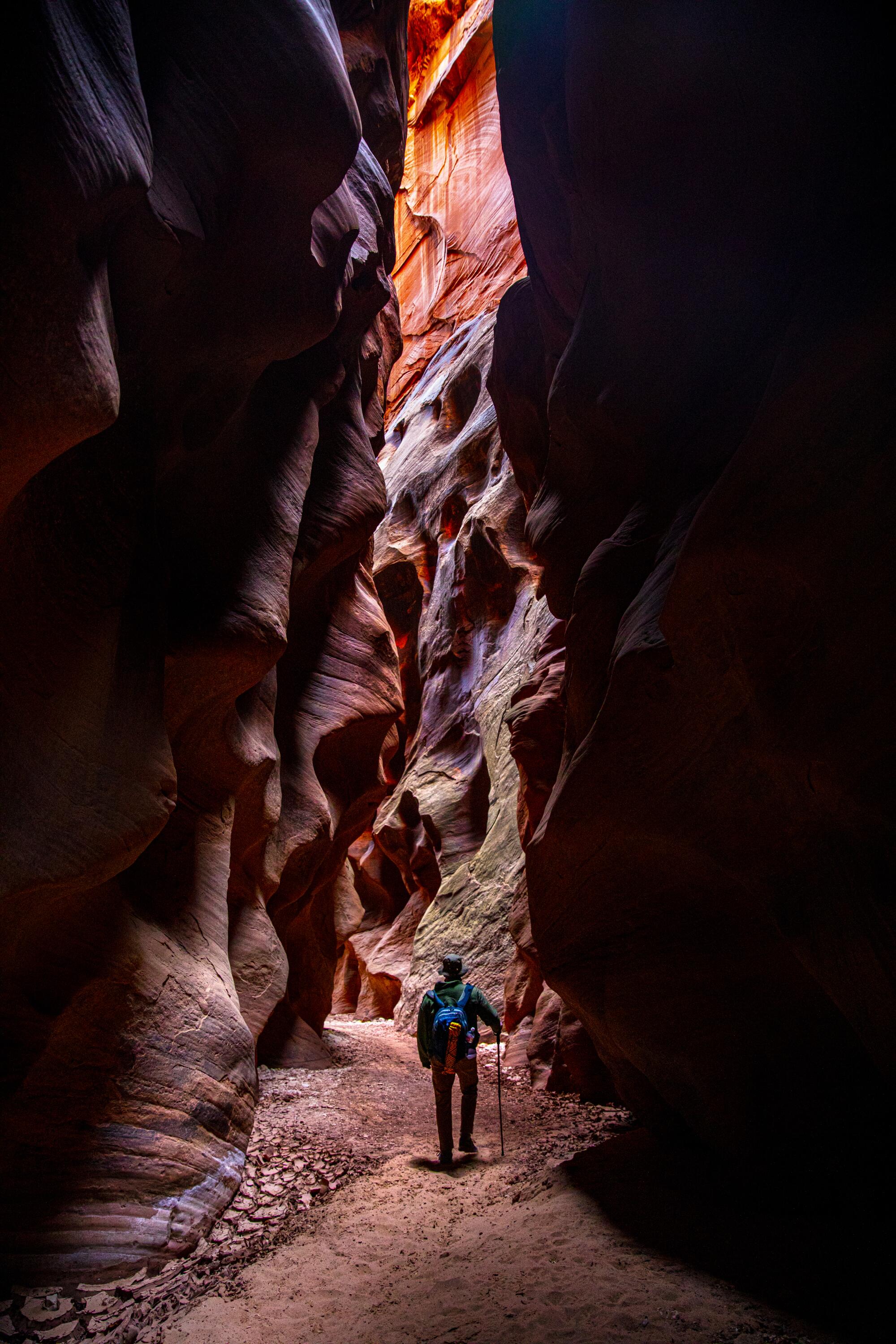 A hiker walks through a narrow canyon 