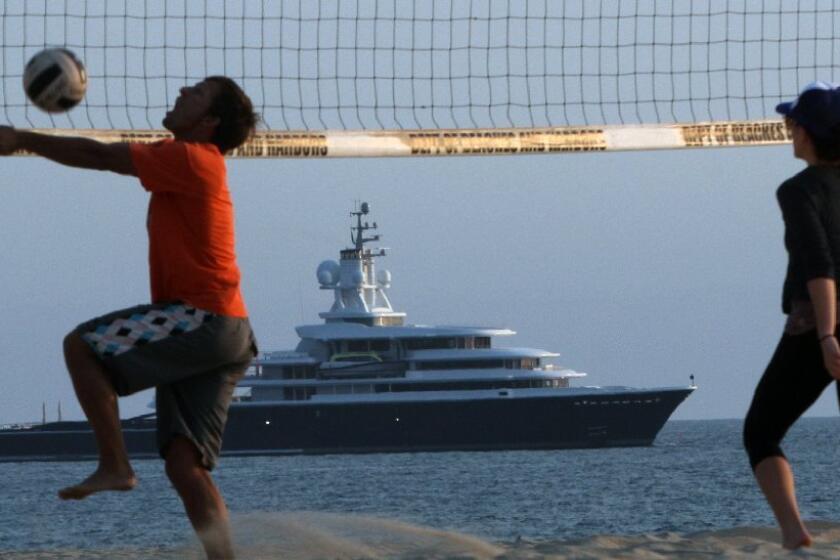 Mark Gelazela goes for a ball as Sara Safadi backs him up as they play volleyball at Venice Beach. In the distance, the 377-foot-long mega-yacht the Luna, owned by Russian billionaire Roman Abramovich, sits off the beach just north of the Marina del Rey harbor entrance on Tuesday.