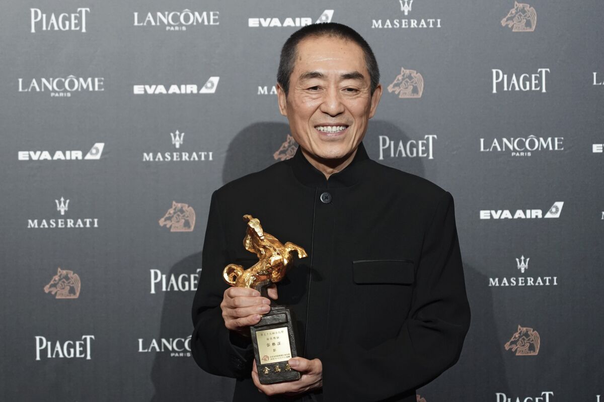 FILE - In this Saturday, Nov. 17, 2018, file photo, Chinese director Zhang Yimou holds his award for Best Director at the 55th Golden Horse Awards in Taipei, Taiwan. Renowned Chinese filmmaker Zhang Yimou is promising a simpler opening ceremony for the Beijing Winter Games with a bold and unprecedented way of lighting the Olympic flame. (AP Photo/Billy Dai, File)