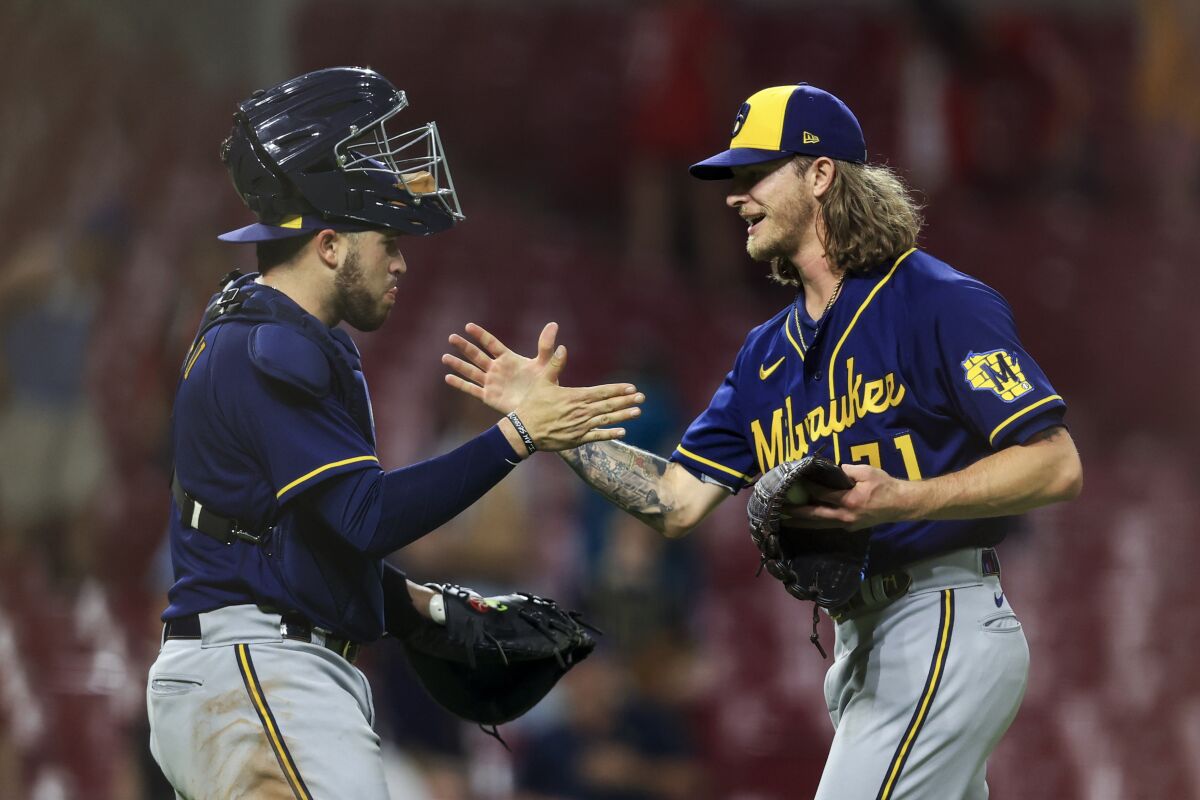 Milwaukee Brewers' Victor Caratini, left, high-fives Josh Hader after the final out a baseball game against the Cincinnati Reds in Cincinnati, Tuesday, May 10, 2022. The Brewers won 5-4. (AP Photo/Aaron Doster)