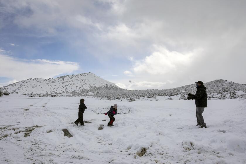 Phelan, CA - January 29: Adrian Rios, right, and his children Ian Rios, left, and Susan Rios play in freshly fallen snow along Highway 138 on Friday, Jan. 29, 2021 in Phelan, CA.(Irfan Khan / Los Angeles Times)