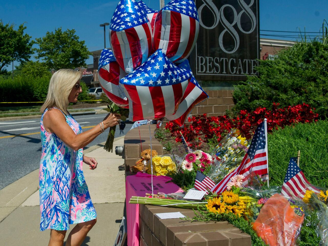 A woman delivers flowers at a memorial to shooting victims at the Capital newspaper in Annapolis, Md.