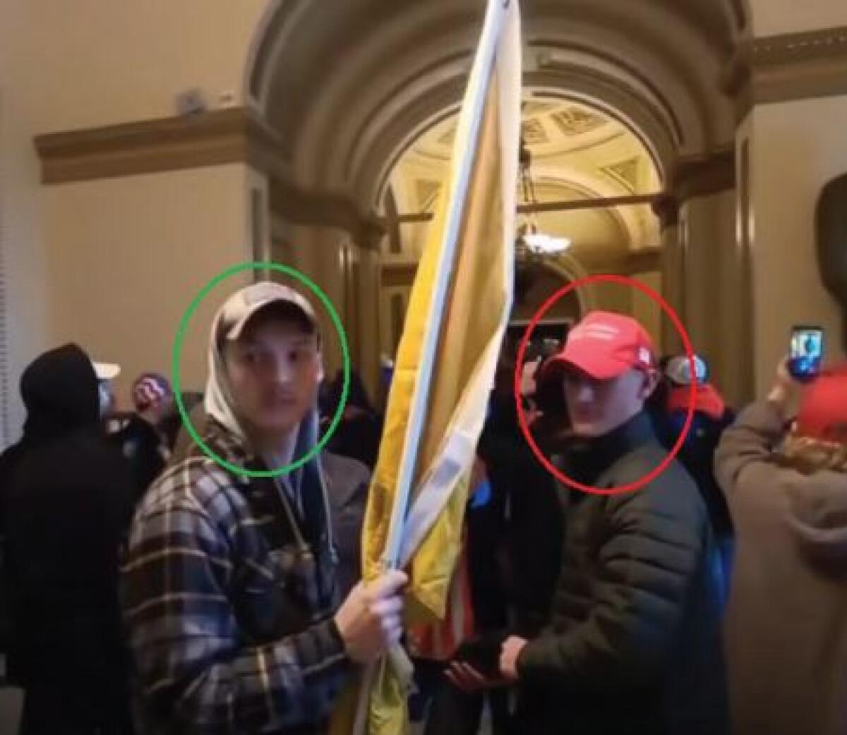Two men carrying a flag among a mob inside the Capitol