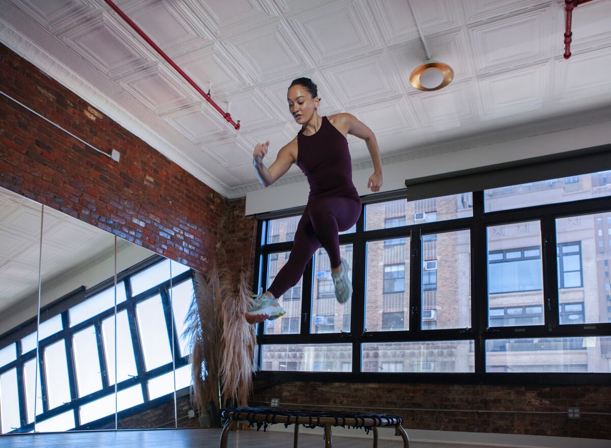 A woman rebounds into the air during a workout on a mini trampoline at a bouncing studio in New York City.