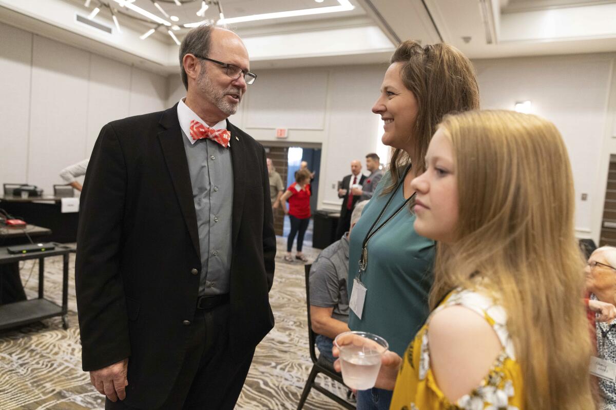 From left, Douglas Frank chats with Melissa Sauder and her daughter, Anley, 13, of Grant, Neb., before the start of the Nebraska Election Integrity Forum on Saturday, Aug. 27, 2022, in Omaha, Neb. (AP Photo/Rebecca S. Gratz)