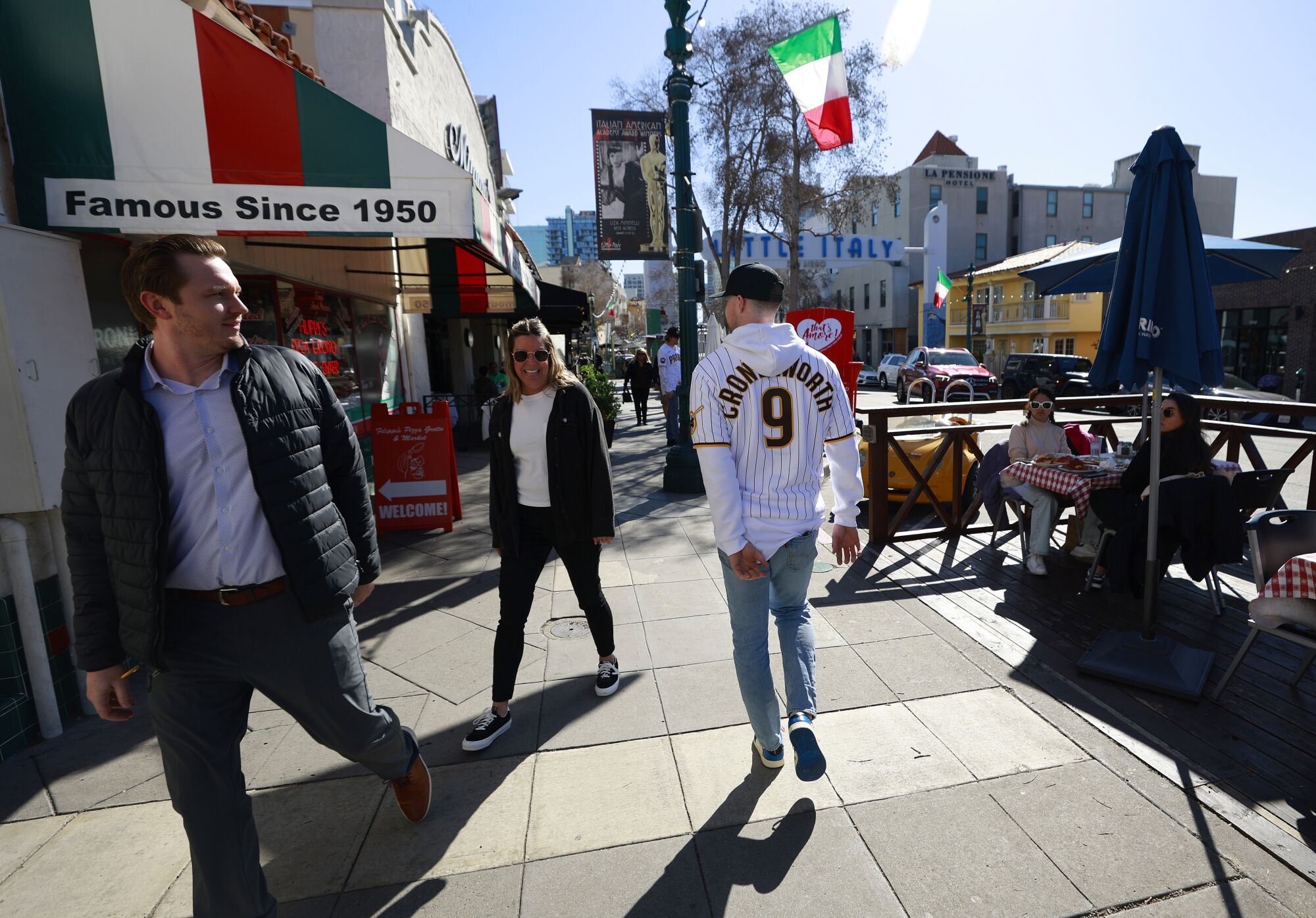 Padres' Jake Cronenworth walks down the sidewalk in Little Italy as players spread 