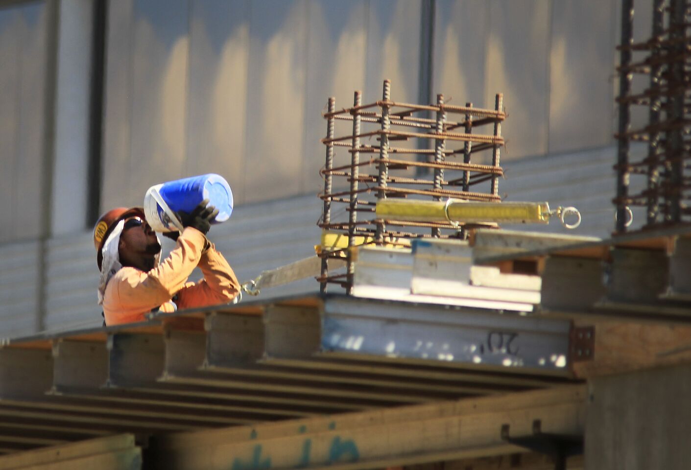 A construction worker takes a long drink from a insulated jug while taking a break at The Village, under construction at Westfield Topanga in Woodland Hills.