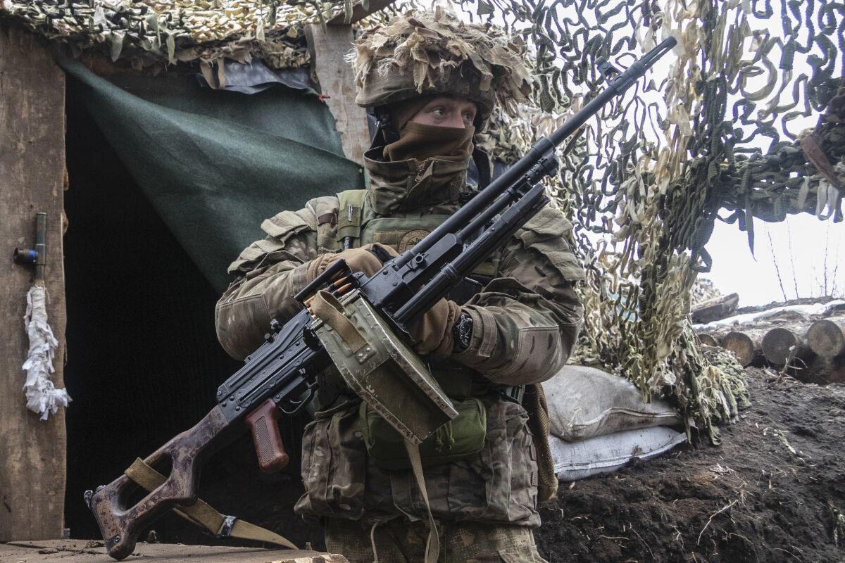 Armed Ukrainian soldier in a camouflaged front-line outpost
