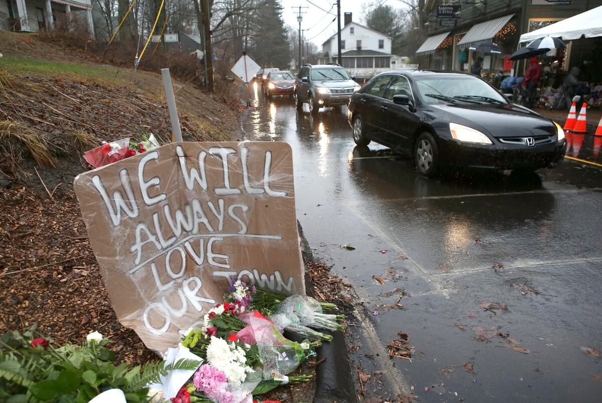 Cars glide by the memorial in Newtown, Conn., before the moment of silence Friday morning.