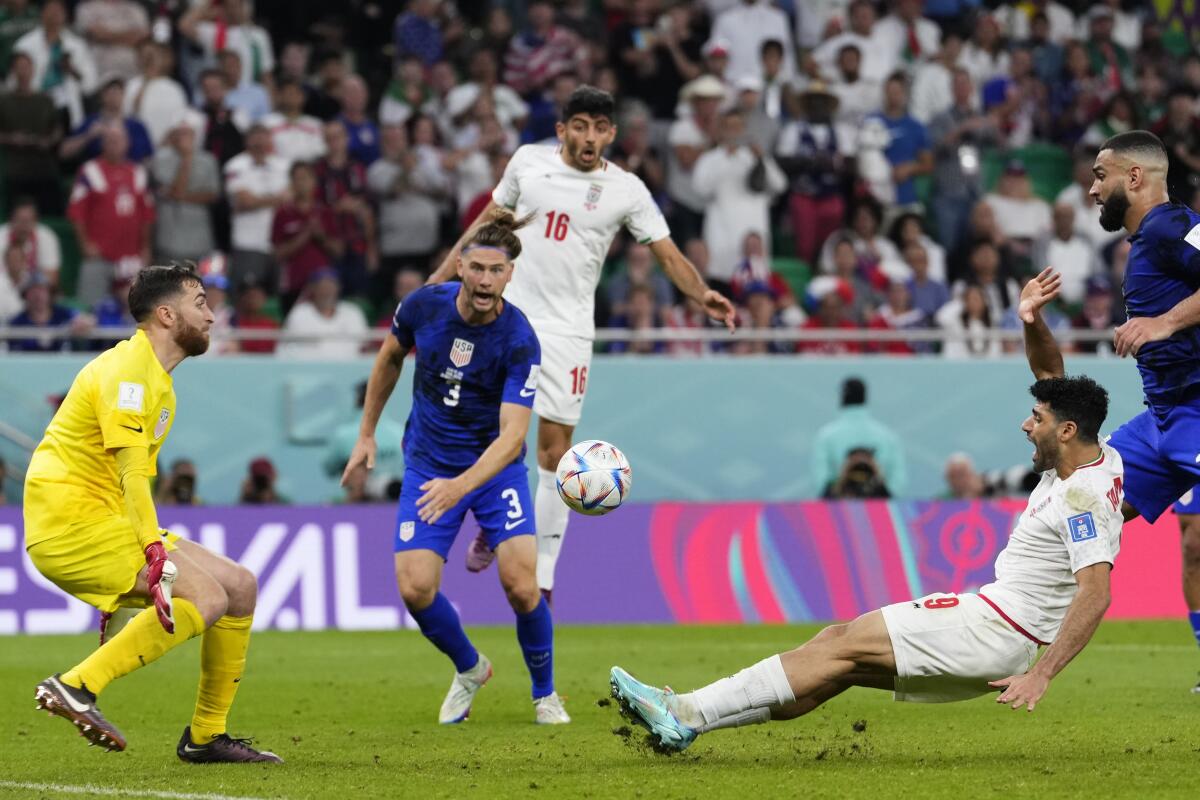 Iran's Mehdi Taremi, right, takes a shot as U.S. goalkeeper Matt Turner squares up to make a save.