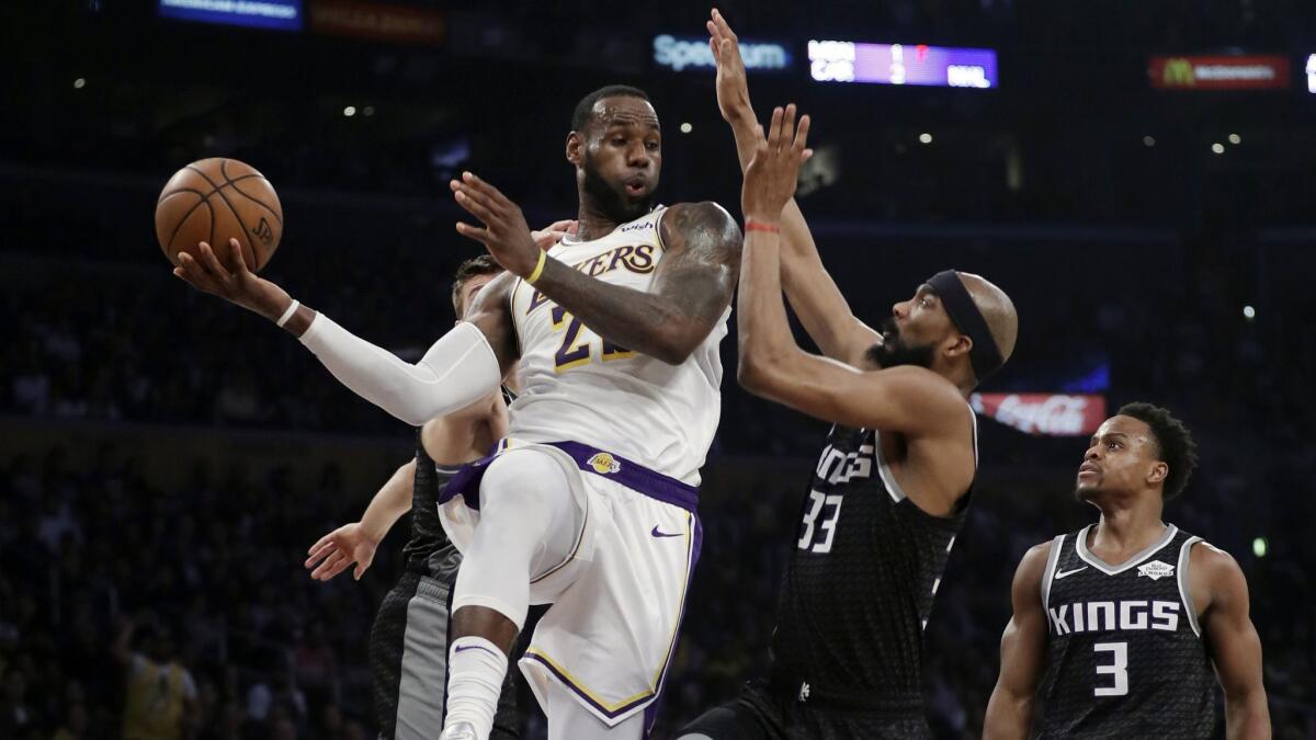 Lakers forward LeBron James makes a behind-the-back pass while defended by Kings forward Corey Brewer during the first half Sunday.