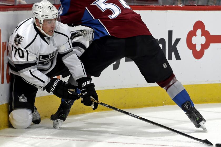 Kings forward Tanner Pearson tries to get the puck to a teammate after battling along the boards against Avalanche defenseman Anton Lindholm during the second period Friday.