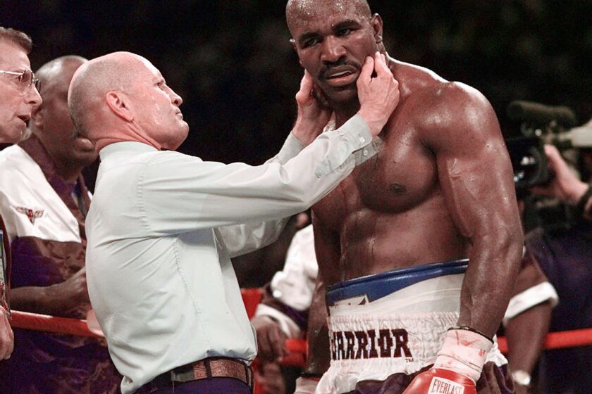 ARCHIVO - En foto del 28 de junio de 1997, el referí Mills Lane revisa la oreja del boxeador Evander Holyfield después de que Mike Tyson mordió su oreja en el tercer round de la pelea. El martes 6 de diciembre del 2022, Lane falleció a los 85 años. (AP Foto/Mark J. Terrill, File)