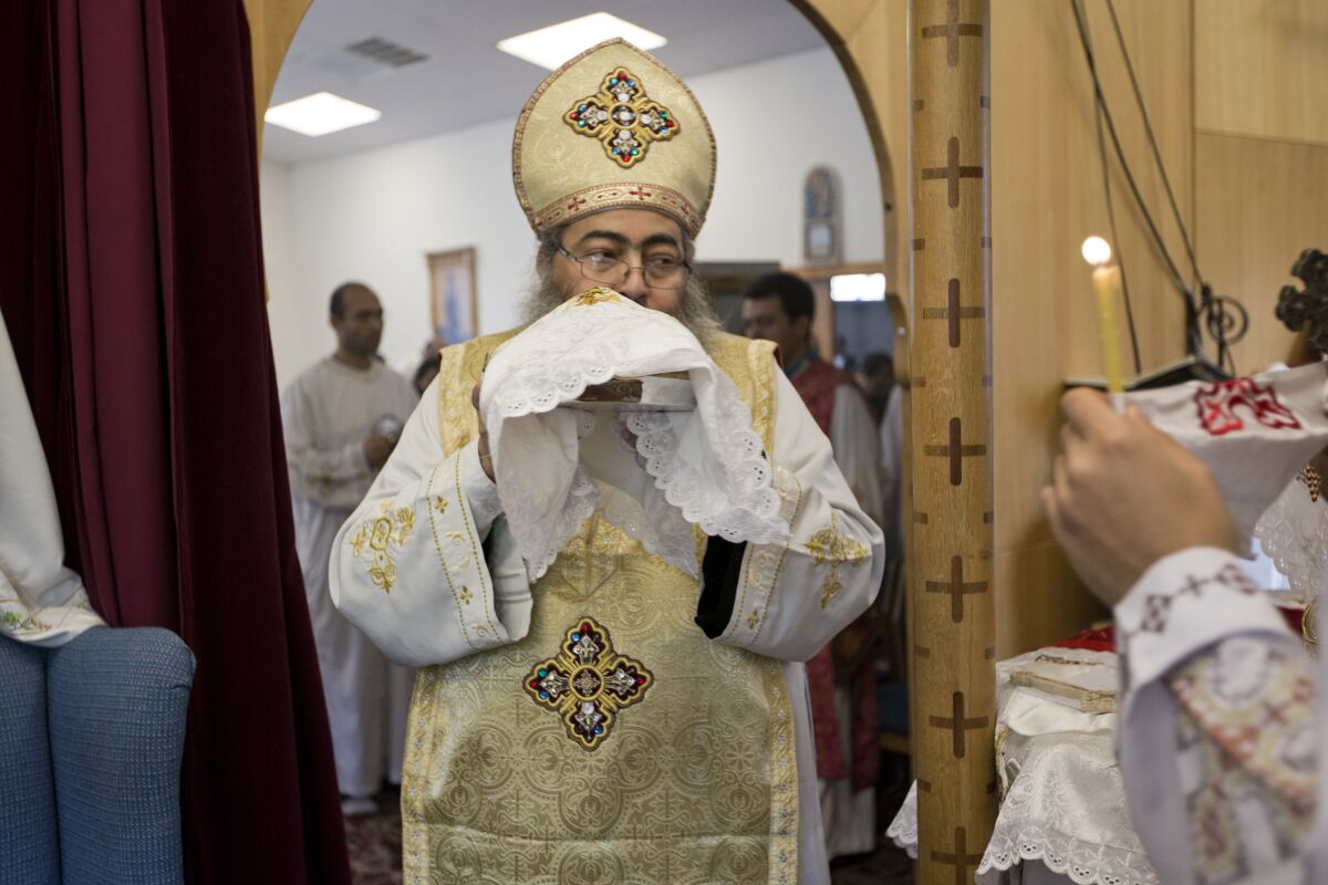 In this Sunday, Aug. 18, 2013 photo, Father Reweis Khalil brings the bread (Body of Christ) to worshippers during Sunday service at St. George Coptic Orthodox Church in Hampton, VA., on Sunday, Aug. 18, 2013. Khalil was removed from the priesthood in July. Sally Zakhari has alleged, including in a police report and to Coptic Church officials, that Khalil has sexually abused her. Khalil has denied the allegations through his attorney. (The' N. Pham/The Virginian-Pilot via AP)