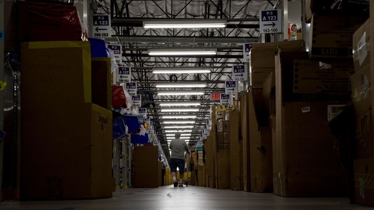 A worker collects items for customer orders on Cyber Monday at an Amazon warehouse in San Bernardino.