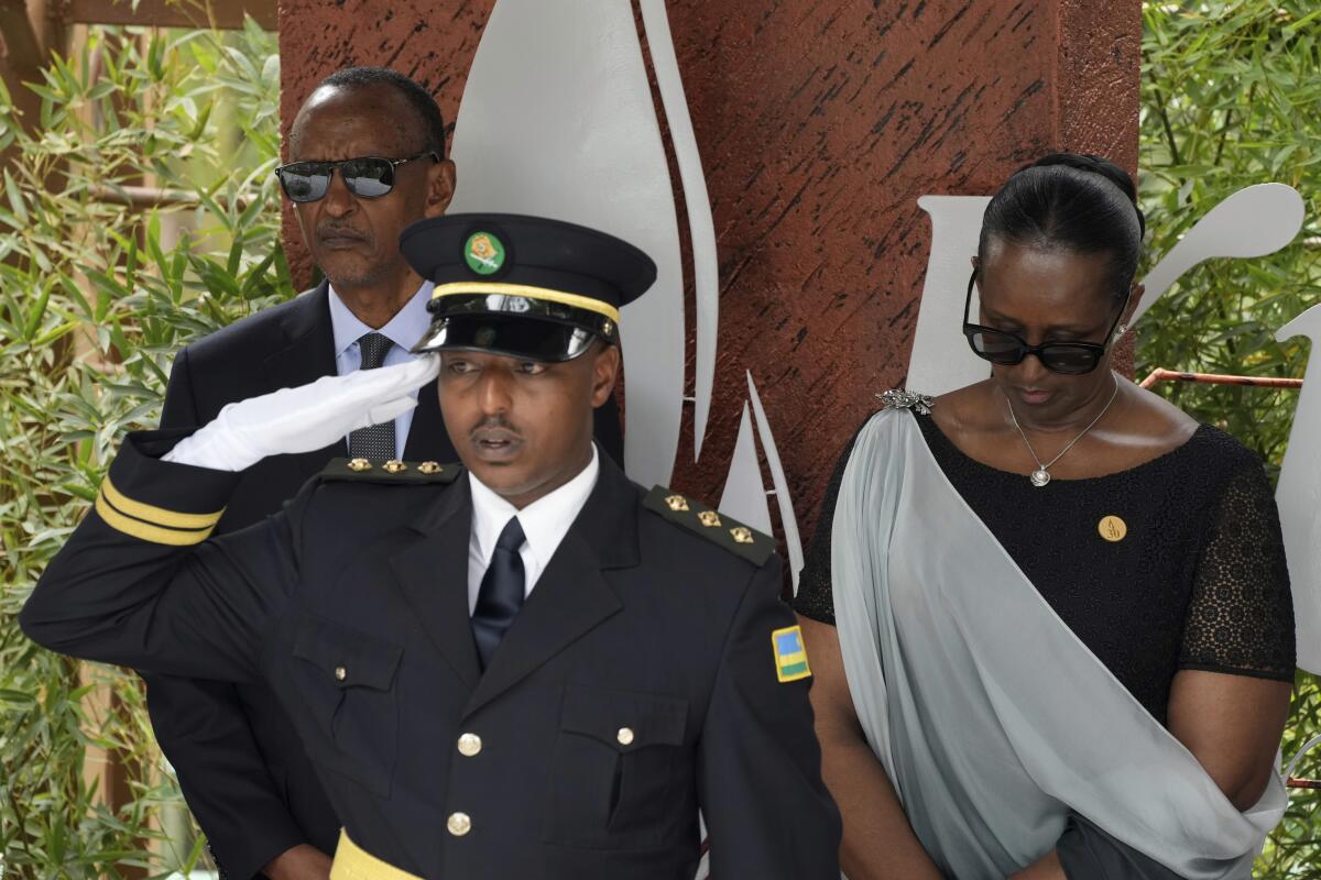 Rwandan President Paul Kagame, background left, and his wife, first lady Jeannette Kagame prepare to lay a wreath.