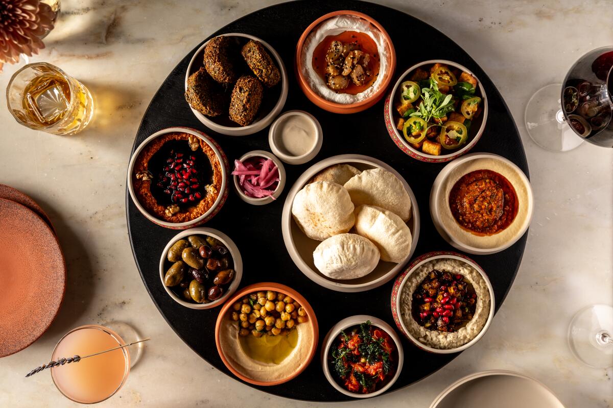 A round dish of smaller round dishes filled with assorted mezze, sauces and puffy breads