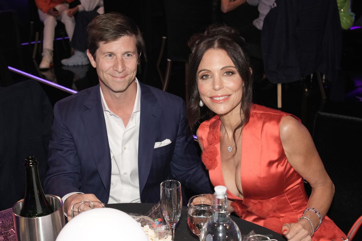 Paul Bernon and Bethenny Frankel in evening wear while sitting at a set table